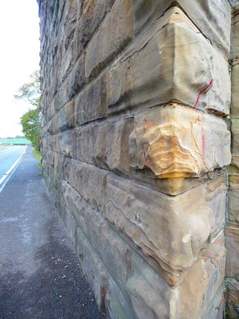 Zdjęcie przedstawia fragment muru. Jest zbudowany z skalnych prostopadłościanów. Ich zewnętrzna warstwa kruszy się, jest popękana.  