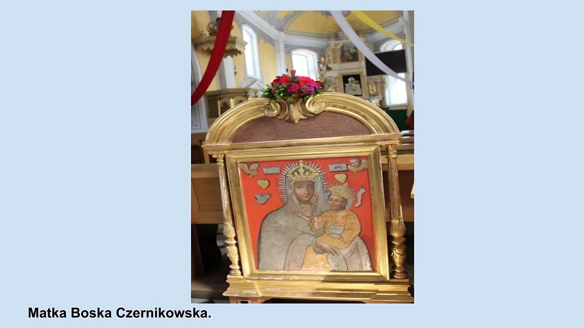 Ilustracja przedstawia ikonę Matki Boskiej Czernikowskiej. Matka biska w złotej koronie i srebrnych szatach trzyma na rękach małą postać Jezusa w złotej koronie i w złotej szacie, na około nich srebrzyste poświaty. Z tyłu czerwone tło, w górnych rogach małe postaci aniołków. Obraz w złotej, rzeźbionej ramie zwieńczonej czerwono różowymi kwiatami. W tle kościół. 