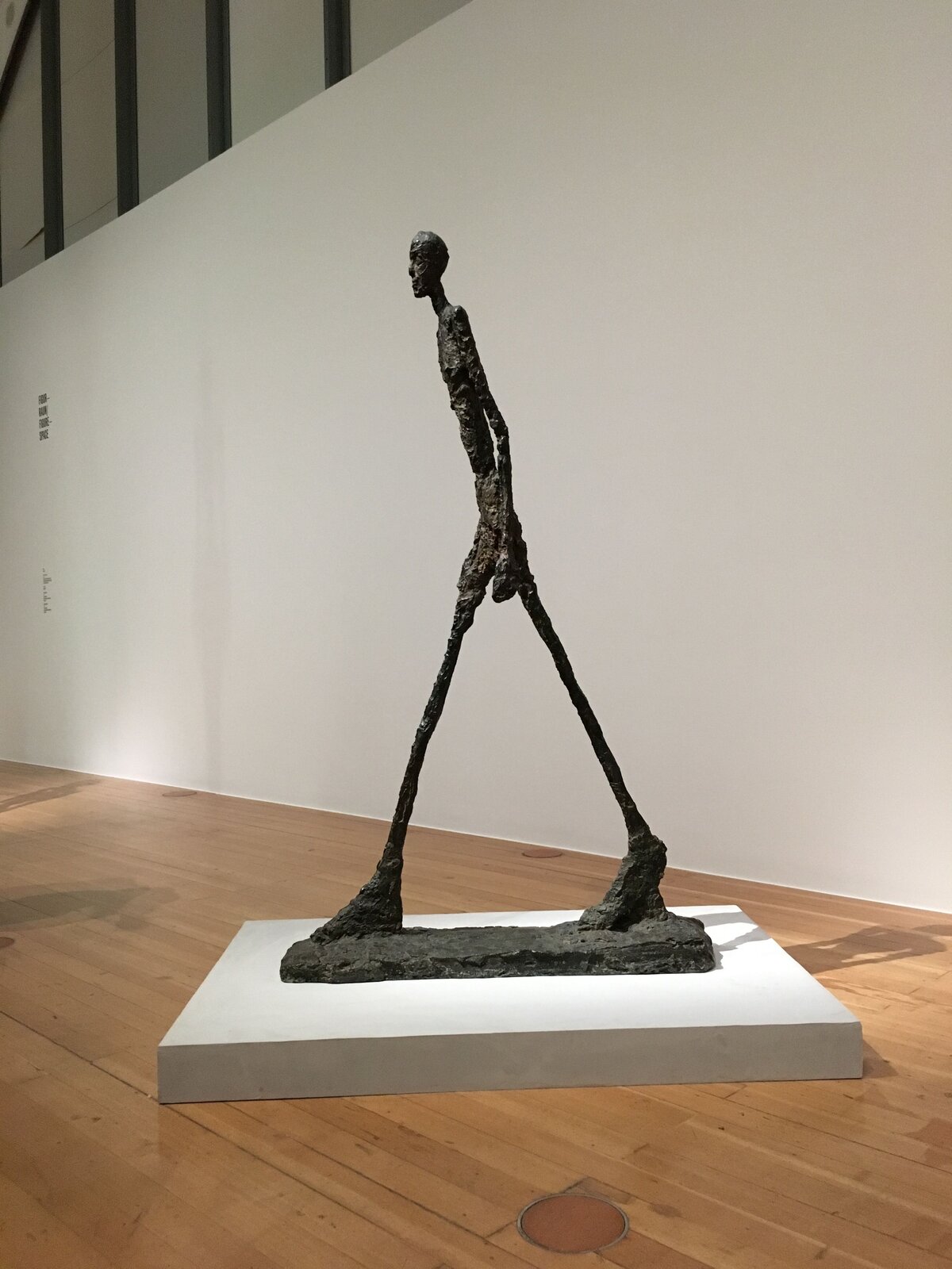 Ilustracja o kształcie pionowego prostokąta przedstawia rzeźbę Alberta Giacomettiego „Idący człowiek”. Przedstawia fotografię rzeźby mężczyzny o konstrukcji szkieletowej, skierowanego w lewą stronę w trakcie ruchu. Nogi postaci są szeroko rozstawione, stopy duże, masywne. Tułów  mężczyzny jest lekko pochylony do przodu, głowa prosto skierowana przed siebie, ręce swobodnie opuszczone. Figura jest pozbawiona proporcji, ustawiona została we wnętrzu na drewnianej podłodze. W tle widoczny jest fragment ściany i balustrady schodów. 