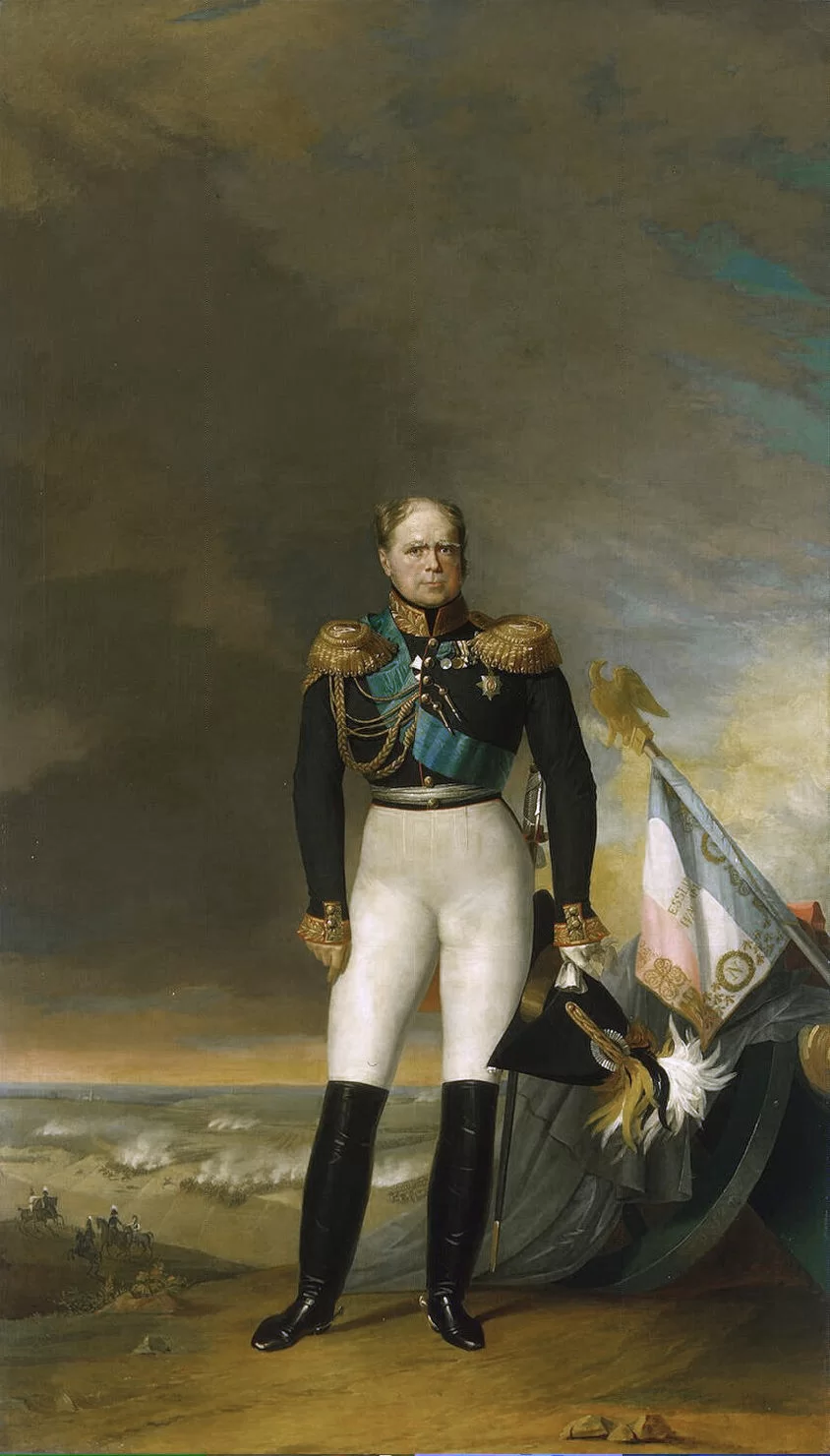 Kliknij żeby powiększyć Na obrazie wysoki mężczyzna. Ubrany jest w mundur z pagonami, na mundurze medale, przepasany grubą szarfą w wysokich skórzanych butach. Obok leżący sztandar zakończony orłem. Na dalszym planie żołnierze na koniach. W tle pole bitwy.