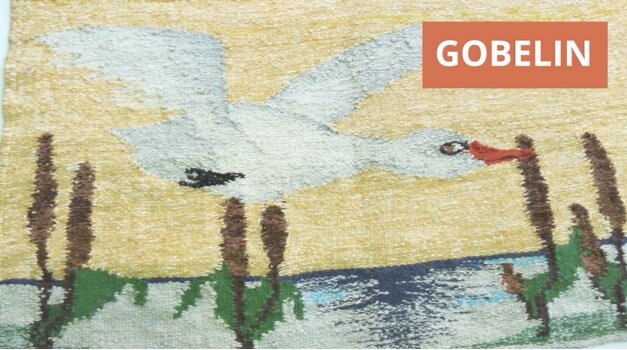 Zdjęcie fragmentu gobelinu, na którym przedstawiony jest lecący, biały ptak nad wodą. 