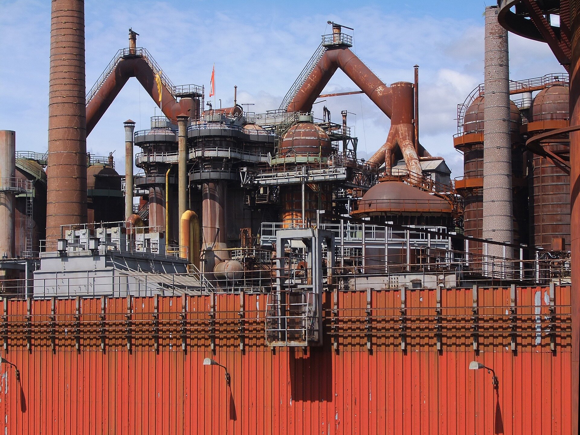 Zdjęcie przedstawia fabrykę. Ma liczne kominy i stalowe konstrukcje. 