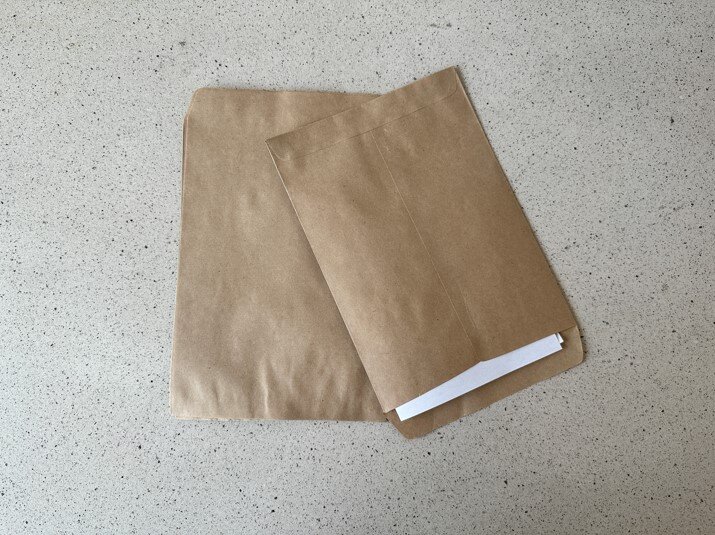 Zdjęcie przedstawia dwie jasnobrązowe koperty wykonane z szarego papieru.