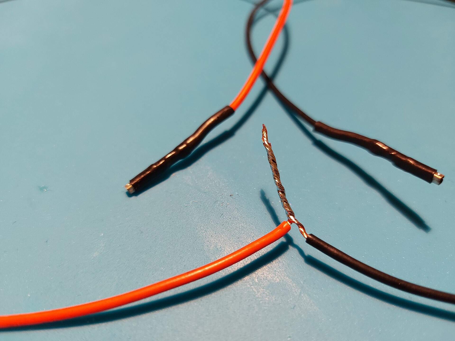 Zdjęcie przedstawia 2 przewody z usuniętą izolacją tym samym odsłaniając miedziane wnętrze, które skręcono ze sobą ustawiając miedziane zakończenia w tym samym kierunku a następnie zlutowano ze sobą.