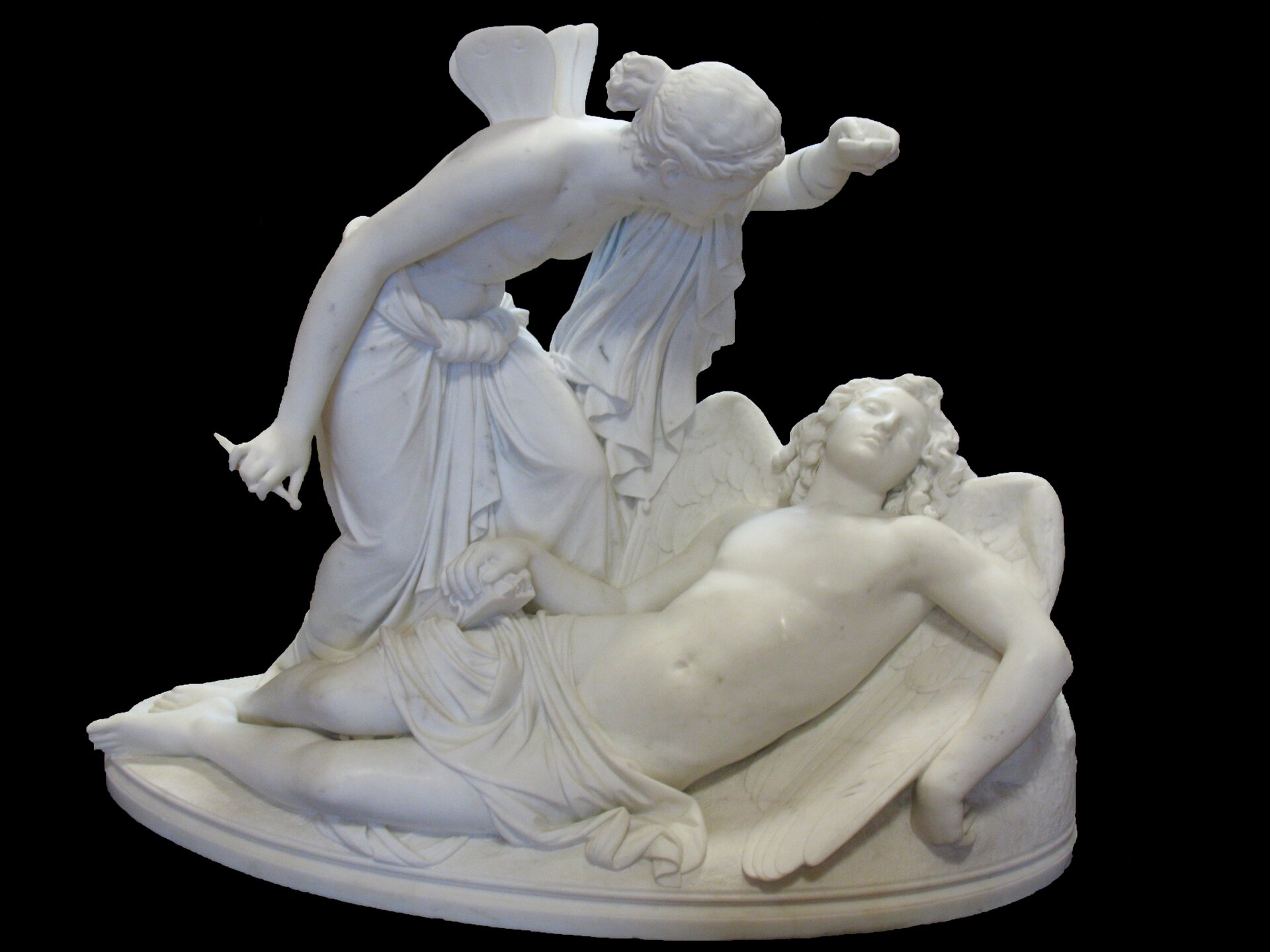 Kliknij, aby powiększyć Fotografia rzeźby przedstawia Psyche pochyloną nad śpiącym bogiem Erosem, na plecach ma małe skrzydełka. W lewej dłoni Psyche unosi lampkę oliwną, natomiast w prawej dłoni trzyma niewielki sztylet. Obie półnagie postacie wyrzeźbiono w białym marmurze. Eros jest okryty niewielką tkaniną, leży na rozłożonych dużych skrzydłach, a Psyche ma tylko tkaninę uwiązaną na biodrach i zwieszającą się na ramieniu.