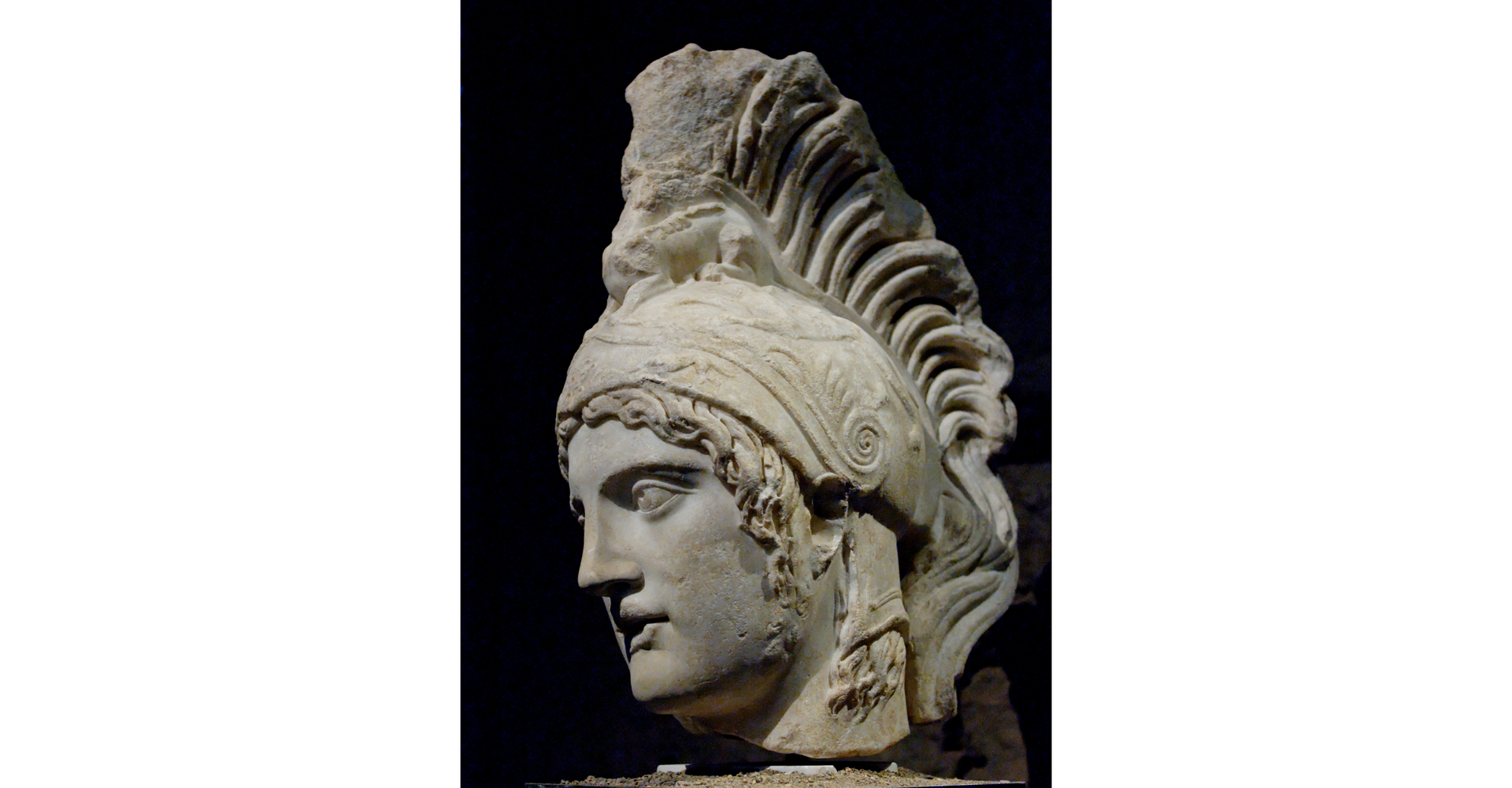 Zdjęcie przedstawia rzeźbę, głowę boga wojny Marsa. Na głowie ma dekoracyjny hełm z ogromnym pióropuszem. 