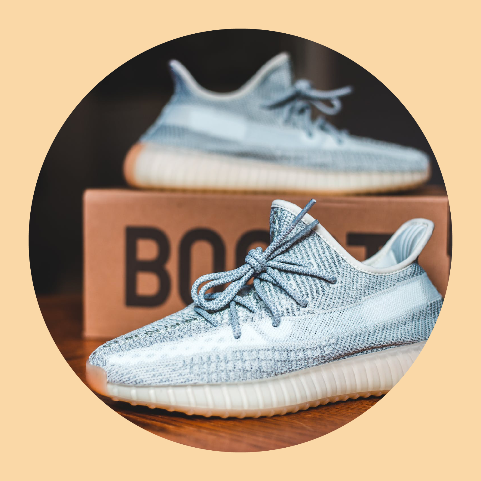 Ilustracja przedstawia parę nowych butów sportowych. Jeden z nich stoi na kartonie, a drugi obok niego.