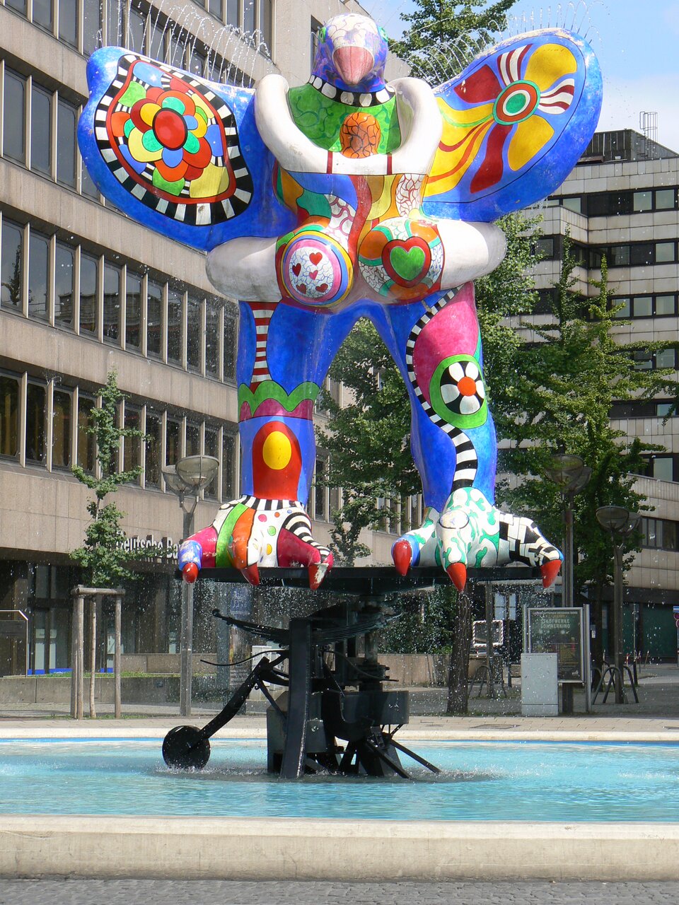 Ilustracja przedstawia pracę Niki de Saint Phalle „Wybawca”. Dzieło powstało w latach 1991‑1993. Możemy je znaleźć w Duisburgu w Niemczech. Na fotografii została przedstawiona fontanna. Na jej szczycie znajduje się kolorowa figura ogromnego ptaka z długimi i ostrymi pazurami. W tle widoczne są wysokie, oszkolone budynki. Autorką pracy jest francuska rzeźbiarka oraz malarka. W swoich pracach bardzo często wykorzystywała motyw kobiecego ciała.