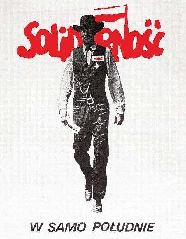 Ilustracja przedstawia plakat wyborczy. Mężczyzna w ubraniu szeryfa znajduje się na środku. W prawej ręce trzyma karteczkę z napisem wybory. Na lewej piersi ma przypinkę z logo Solidarności. Za nim, na wysokości jego głowy i ramion jest duże logo Solidarności składające się z czerwonego napisu solidarność i odchodzącej ku górze z litery n fladze Polski. Na dole plakatu jest napis: W samo południe.