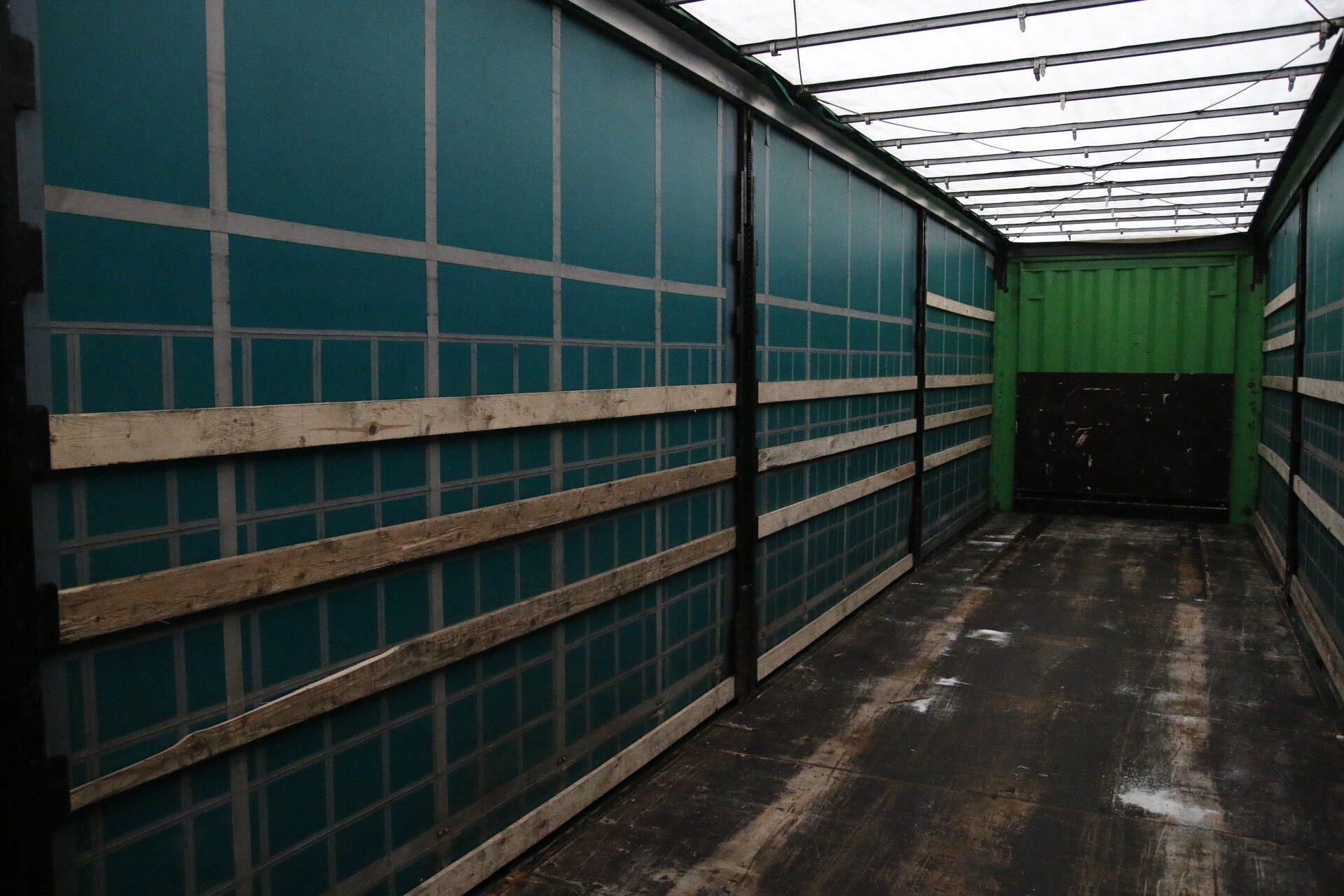 Zdjęcie przedstawia przestrzeń ładunkową, czyli wnętrze naczepy. Ściany naczepy wzmocnione są deskami. Nie posiada ona zadaszenia. 