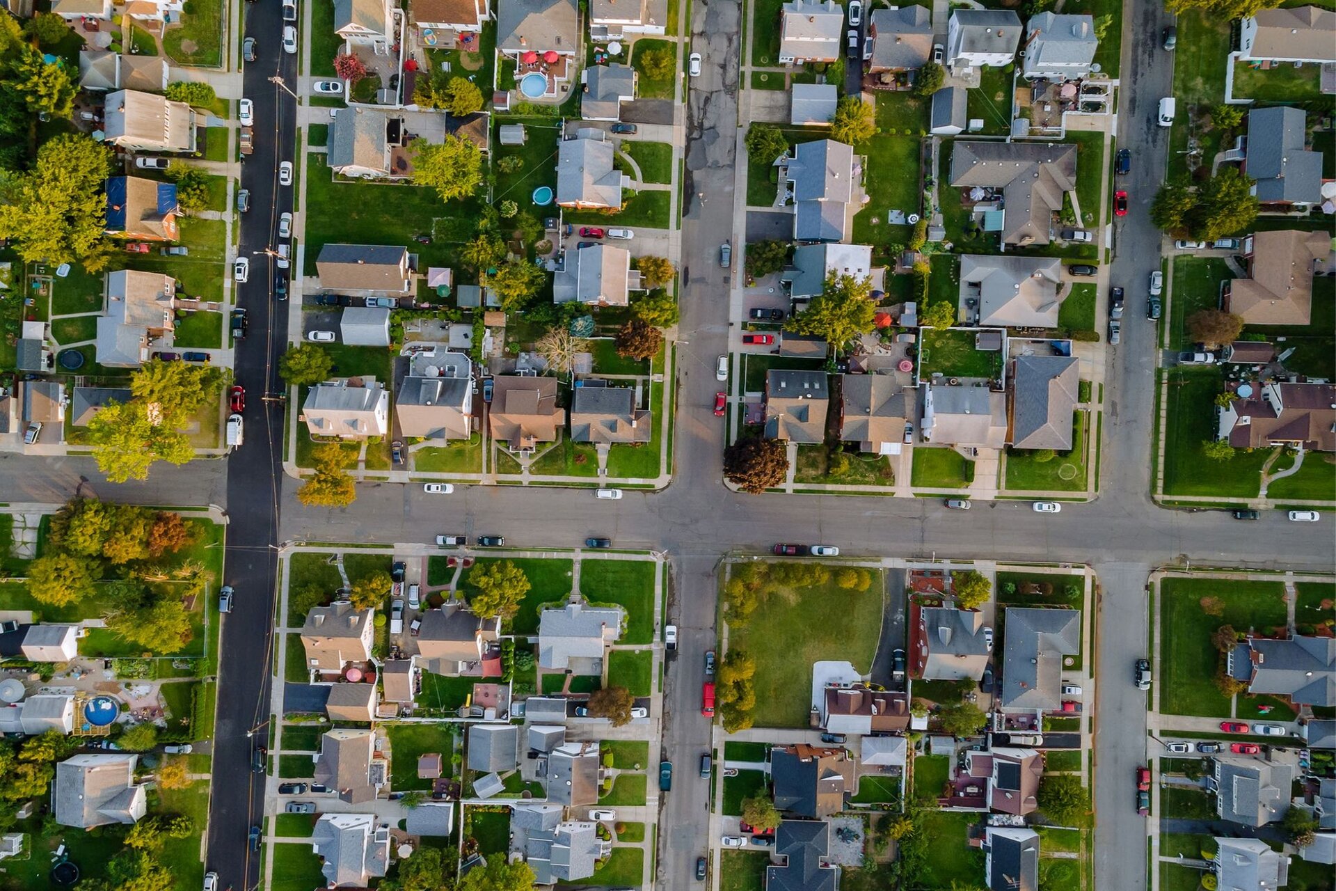 Fotografia wykonana z perspektywy lotu ptaka przedstawia prostopadłą sieć dróg i zabudowania domów jednorodzinnych pomiędzy nimi.