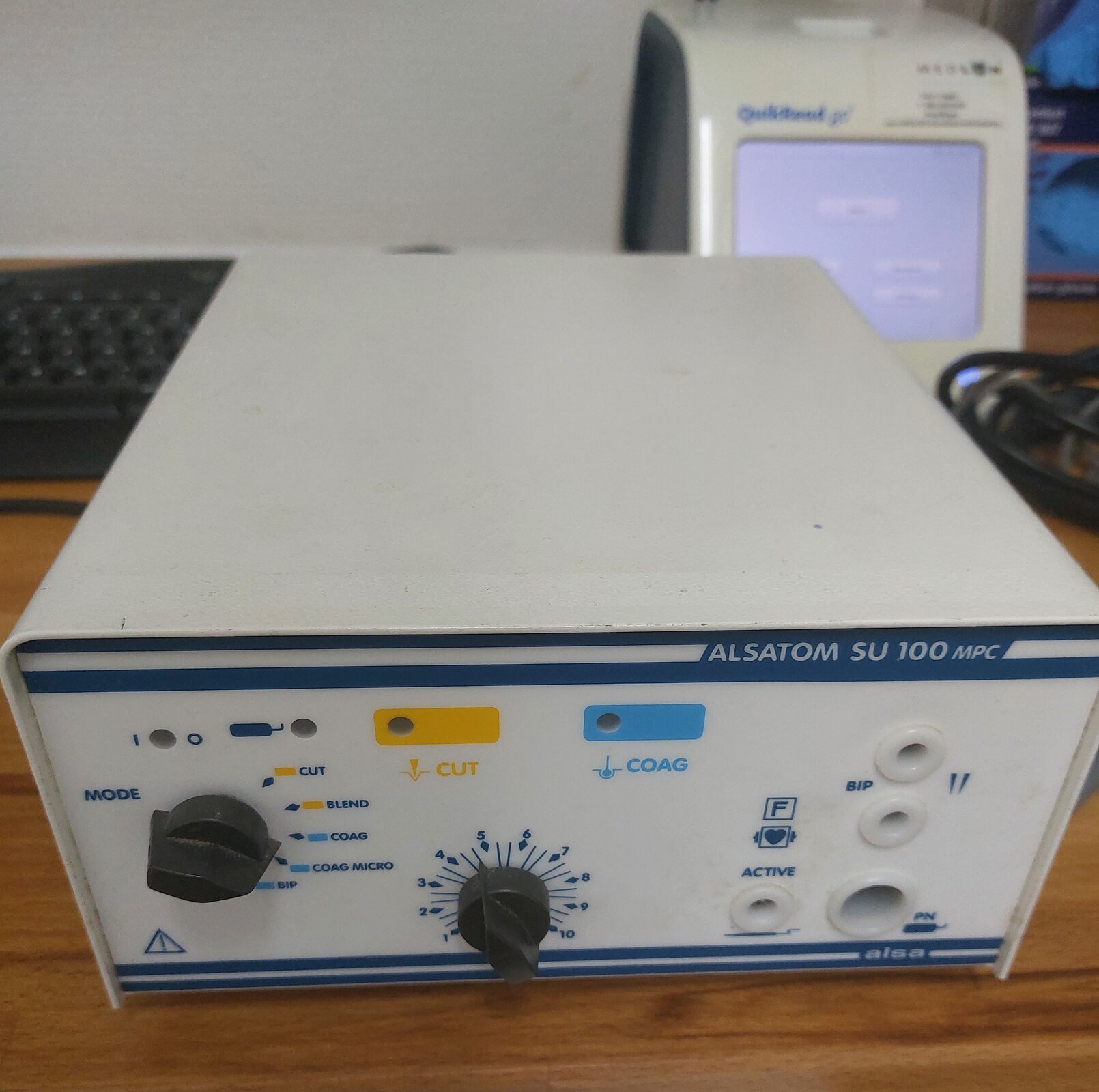 Zdjęcie przedstawia urządzenie do elektrokoagulacji. Na przedniej części obudowy znajdują się dwa pokrętła, opisy parametrów, cztery diody oraz cztery gniazda.