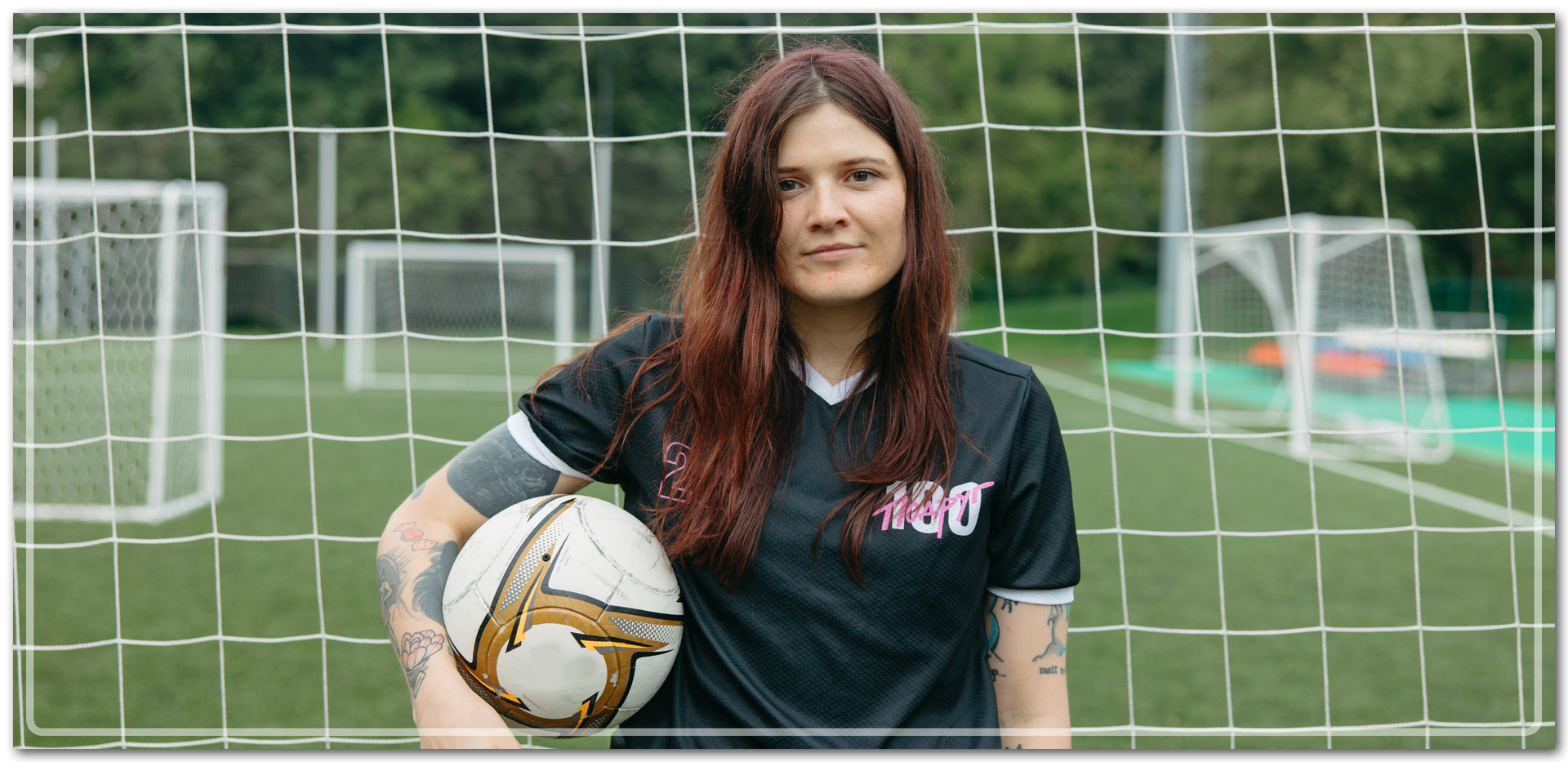Zdjęcie przedstawia dziewczynę, która trzyma piłkę i stoi na tle bramki.