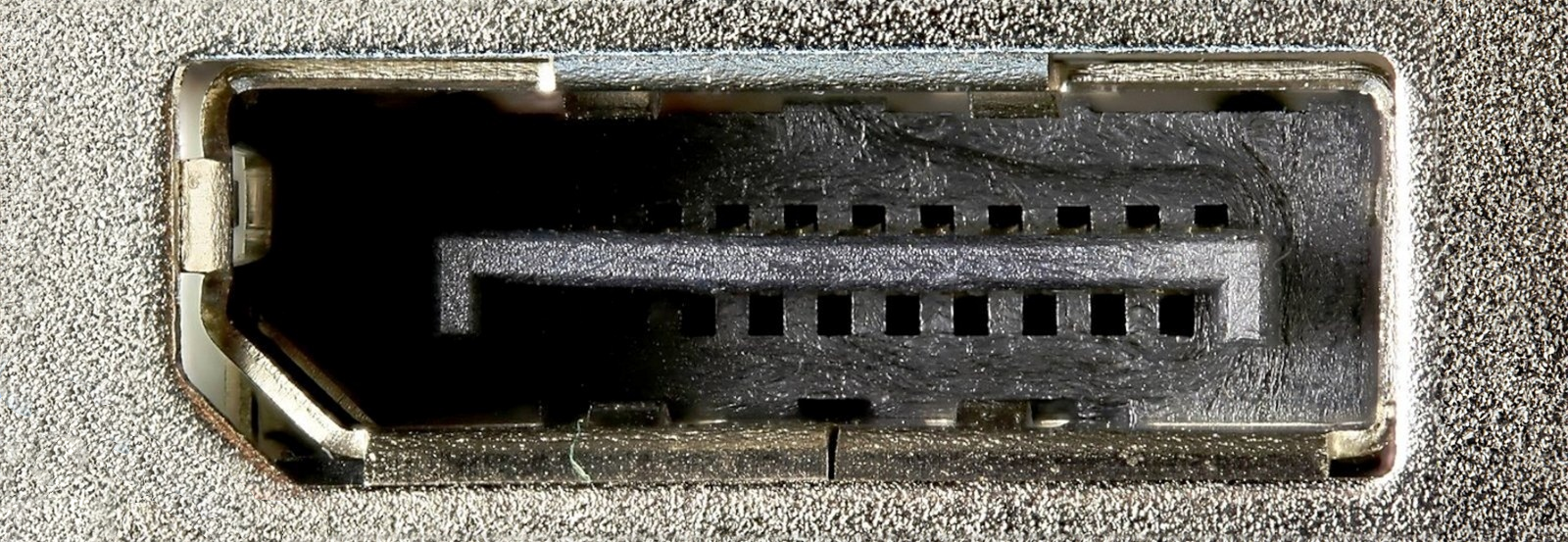 Fotografia przedstawiająca gniazdo DisplayPort - ciemny prostokąt z uciętym lewym dolnym rogiem. W środku znajduje się paręnaście kwadratowych otworów.