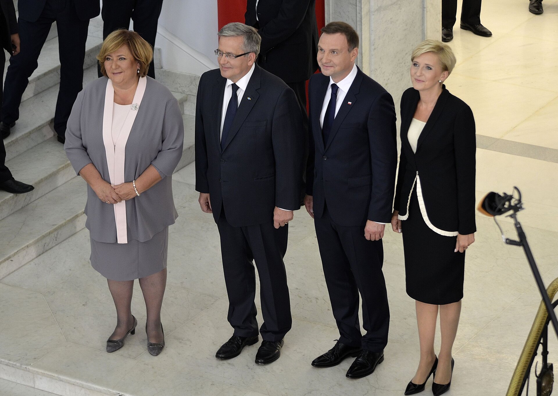Zdjęcie przedstawia stojących obok siebie prezydentów: Bronisława Komorowskiego i Andrzeja Dudę. Obok nich stoją ich żony.