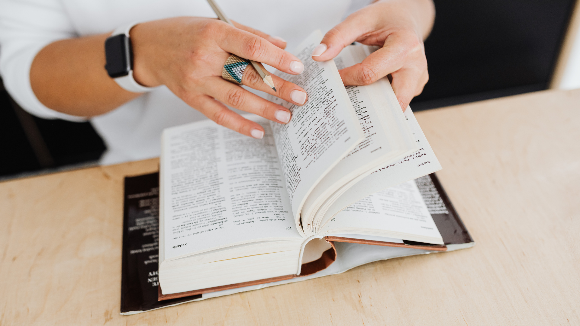 Zdjęcie przedstawia ręce osoby przewracającej kartki w słowniku.