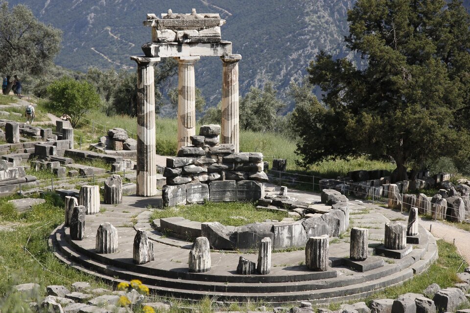 Zdjęcie przedstawia wzgórze, na którym znajdują się wpisane w okrąg ruiny starożytnej świątyni. Widoczne są pozostałości kolumn otaczające świątynię oraz ułożone z bloków kamiennych resztki jej ścian.