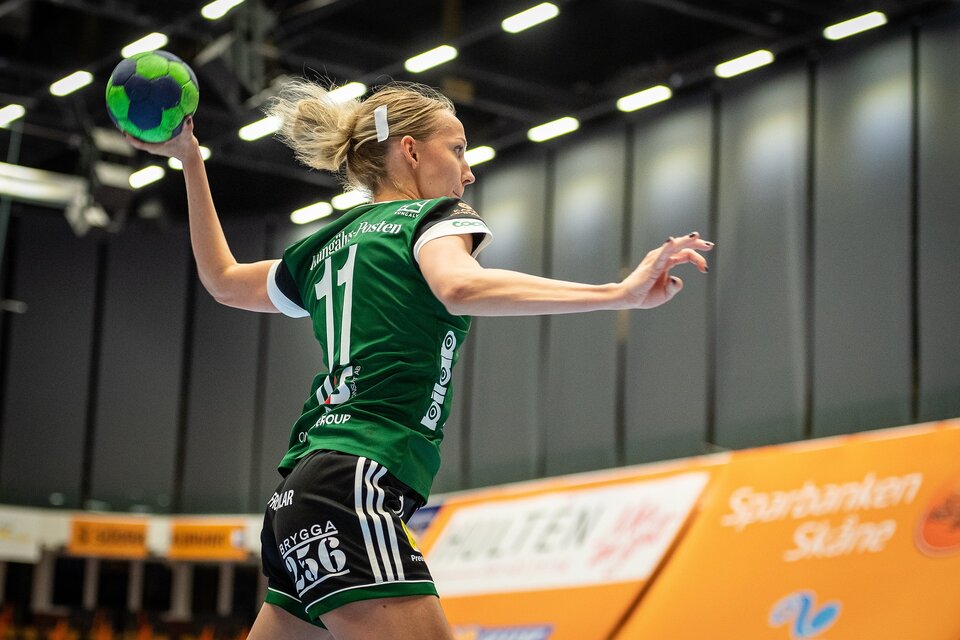 Zdjęcie przedstawia młodą dziewczynę grającą w piłkę ręczną. Ubrana jest w sportowy strój. Lewą ręką, w której trzyma piłkę, wykonuje zamach.