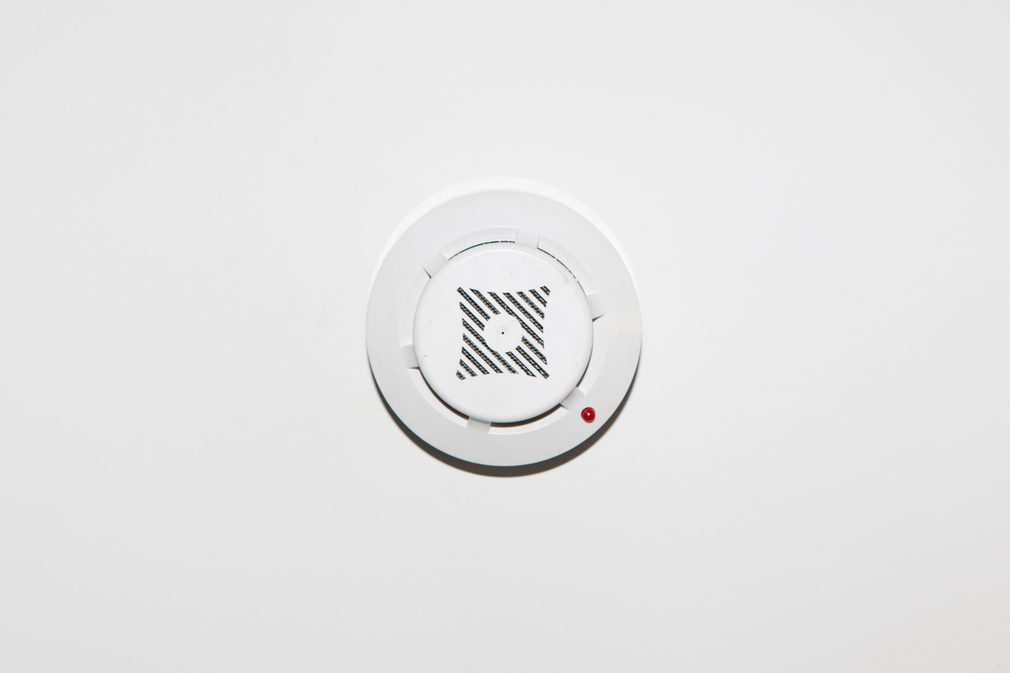 Fotografia przedstawia okrągły, biały czujnik dymu. 