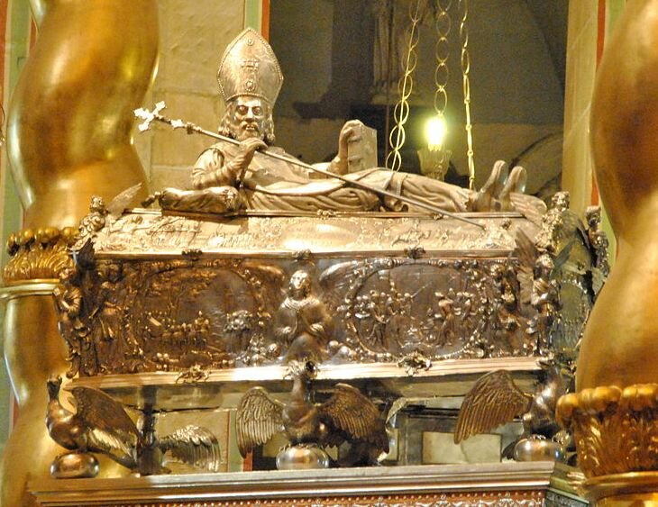 Zdjęcie przedstawia srebrną trumnę świętego Wojciecha, ustawioną na podwyższeniu. U podnóża cokołu widać trzy orły o rozpostartych skrzydłach.  Boki trumny z bogato zdobionymi medalionami przedstawiającymi sceny z życia świętego Wojciecha. W rogach trumny stoją anioły. Na trumnie leży srebrna figura starszego, brodatego mężczyzny. Na głowie ma mitrę, czyli nakrycie głowy, które ma formę wydłużonej czapki, składającej się z dwóch wysokich, połączonych ze sobą trójkątów. Postać podpiera się na prawym łokciu, unosząc nieco plecy i głowę. W prawej dłoni trzyma krzyż osadzony na długiej lasce. Druga dłoń spoczywa na grubej księdze. 