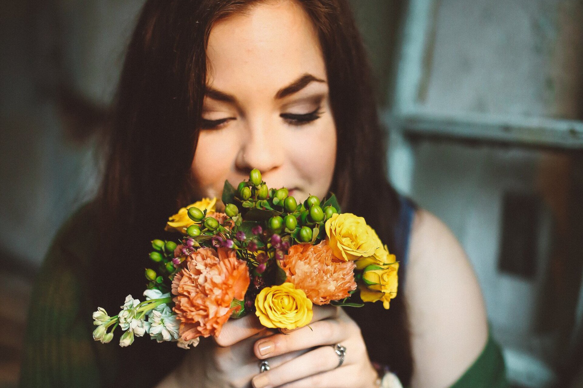 Ilustracja przedstawia kobietę wąchającą kwiaty.