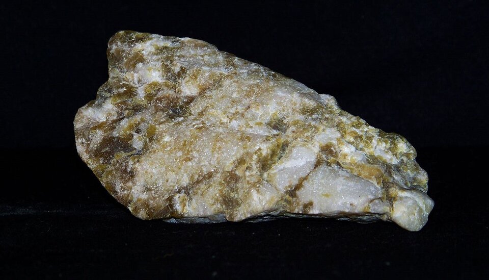 Zdjęcie przedstawia marmur. Posiada gładką powierzchnię o białej barwie z brązowymi pasami.