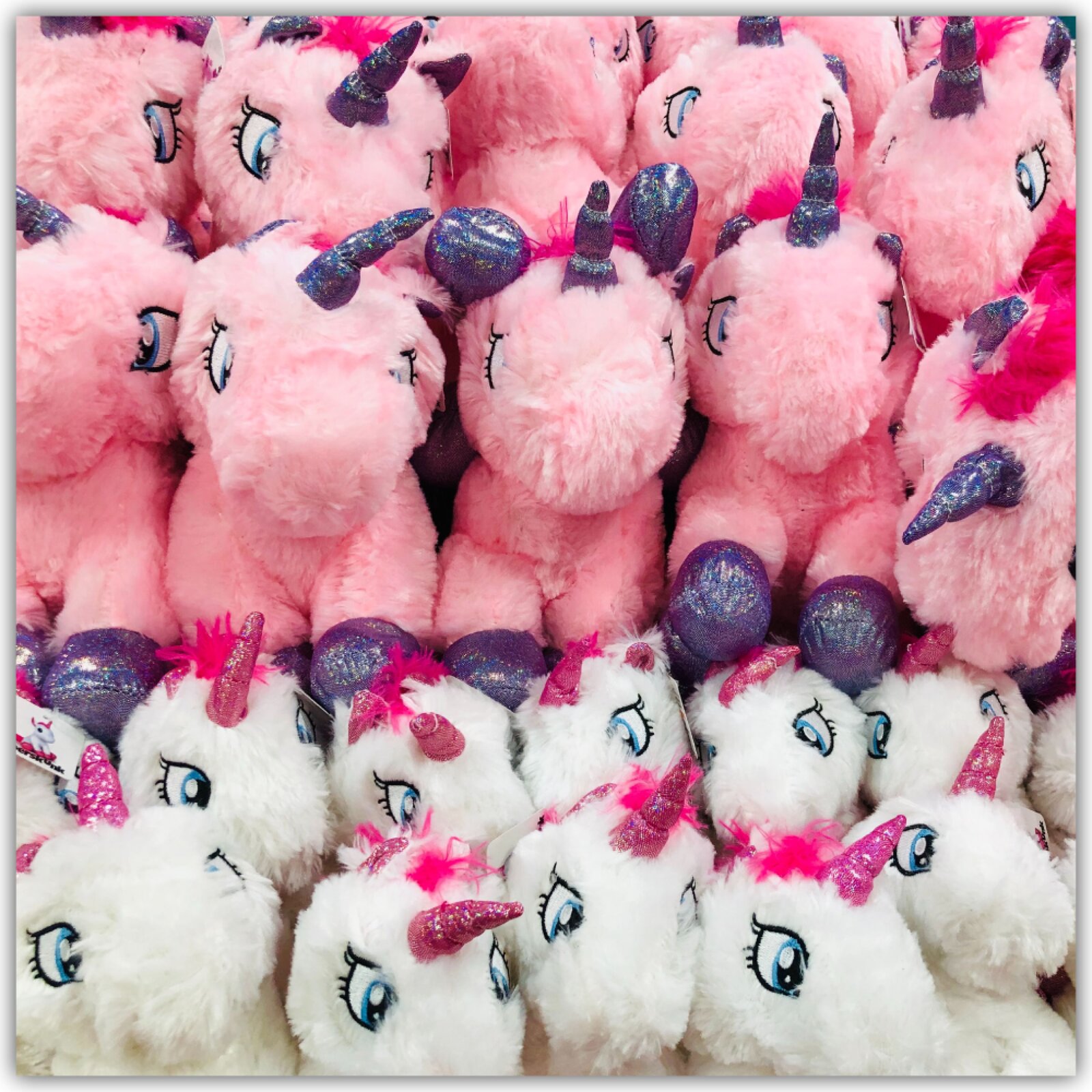 Grafika przedstawia pluszowe jednorożce ułożone w rzędach.