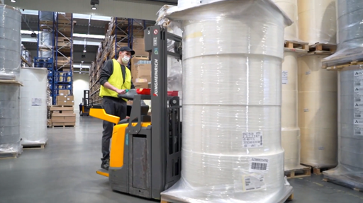 Grafika przedstawia operatora wózka widłowego, który przewozi rure,