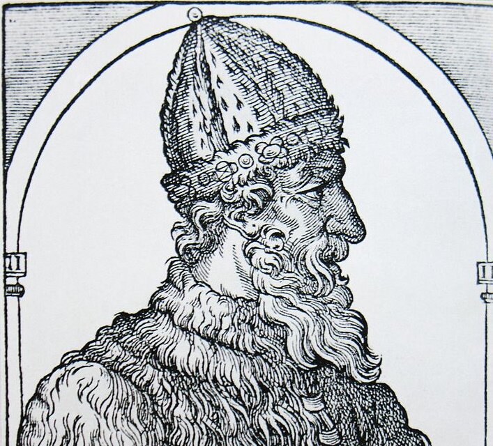 Ilustracja przedstawia portret mężczyzny z profilu. Ma długie wąsy i brodę, a na głowie futrzaną stożkową czapkę.