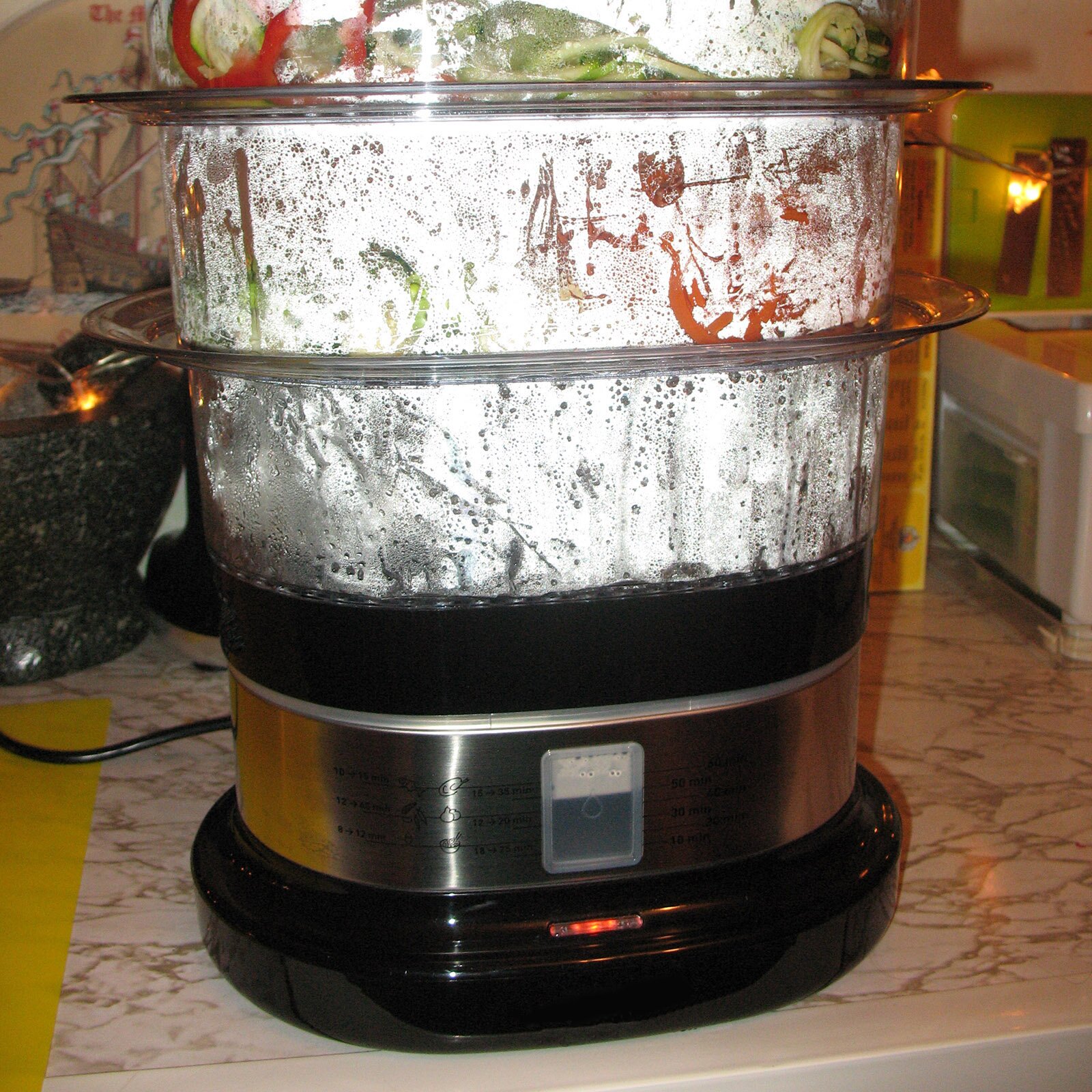 Zdjęcie przedstawia garnek elektryczny, który składa się z kilku nakładanych na siebie pojemników.  Pod zdjęciem transkrypcja [odtwórz]