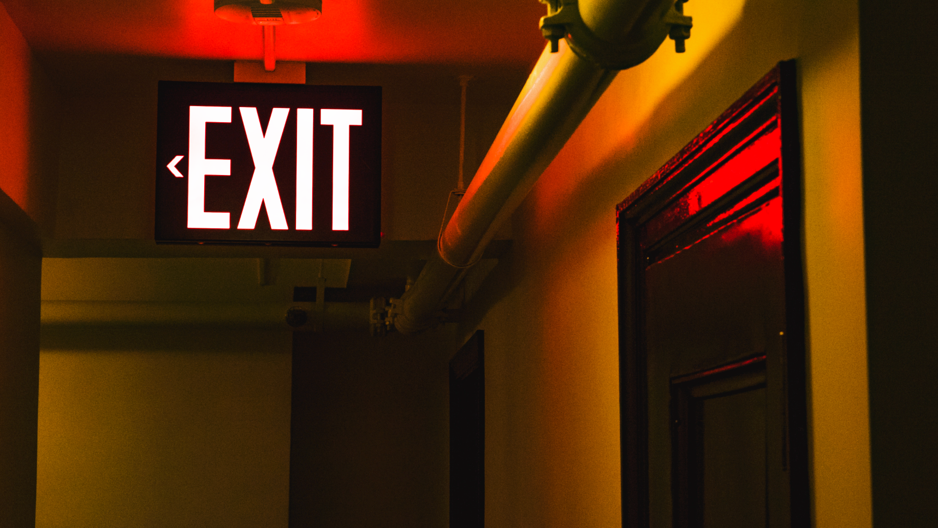 Na zdjęciu widoczny jest duży, podświetlany napis "exit". Neon znajduje się na holu, pod sufitem.