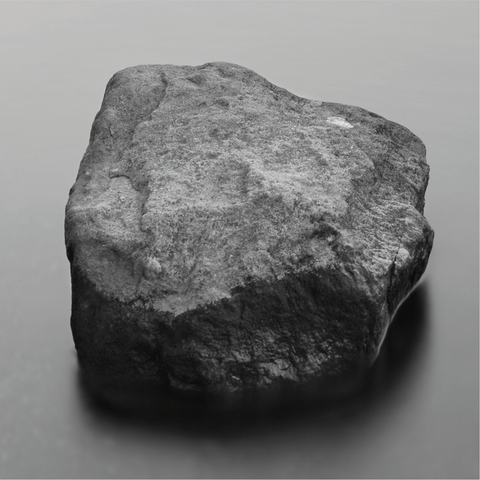 Zdjęcie przedstawia szary kamień, o niejednolitym kształcie i nierównej powierzchni. 