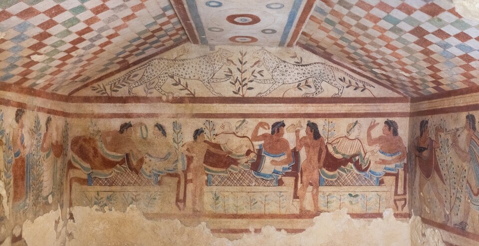 Ilustracja przedstawia ścianę grobowca; na frontonie są pokazane dwa białe, symetrycznie usytuowane lamparty. Poniżej znajduje się fryz ukazujący scenę uczty z udziałem mężczyzn i kobiet. Scena ukazuje elegancko ubrane pary, którym towarzyszą młodzi służący. 