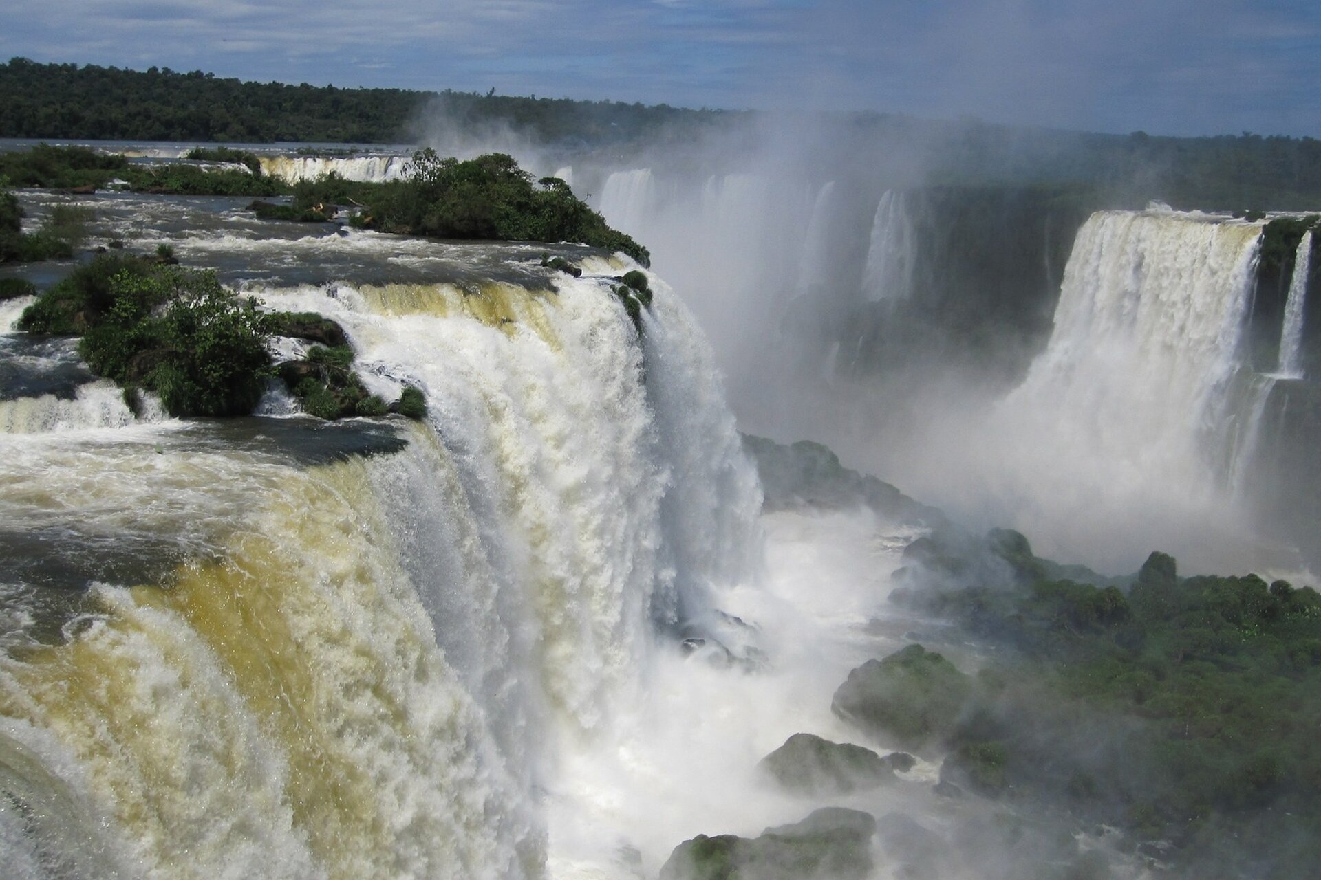 Zdjęcie przedstawia argentyńskie wodospady Igazu znajdujące się na liście Światowego dziedzictwa kulturowego. Ogromne masy wody przelewają się przez strome krawędzie urwiska i rozbijają na skałach na dole, tworząc kurtyny wodne.