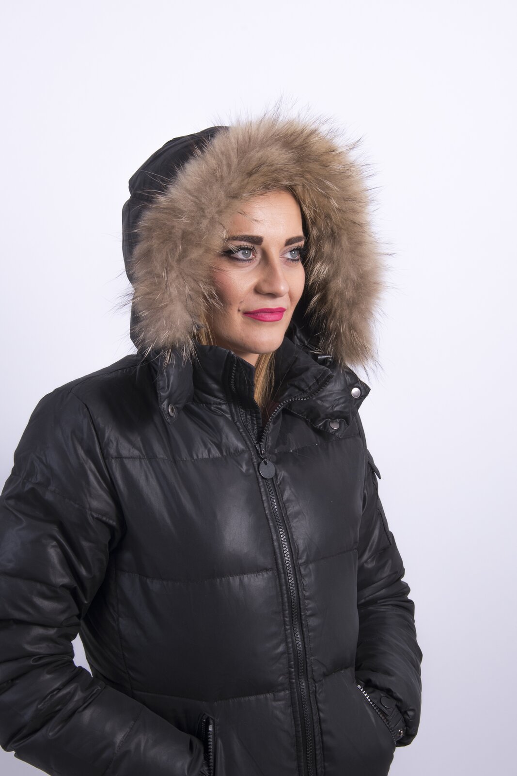 Na zdjęciu widoczna modelka w czarnej kurtce z kapturem. Kołnierz jest obszyty futrem w jasnobrązowym kolorze. Nagranie tożsame z treścią.