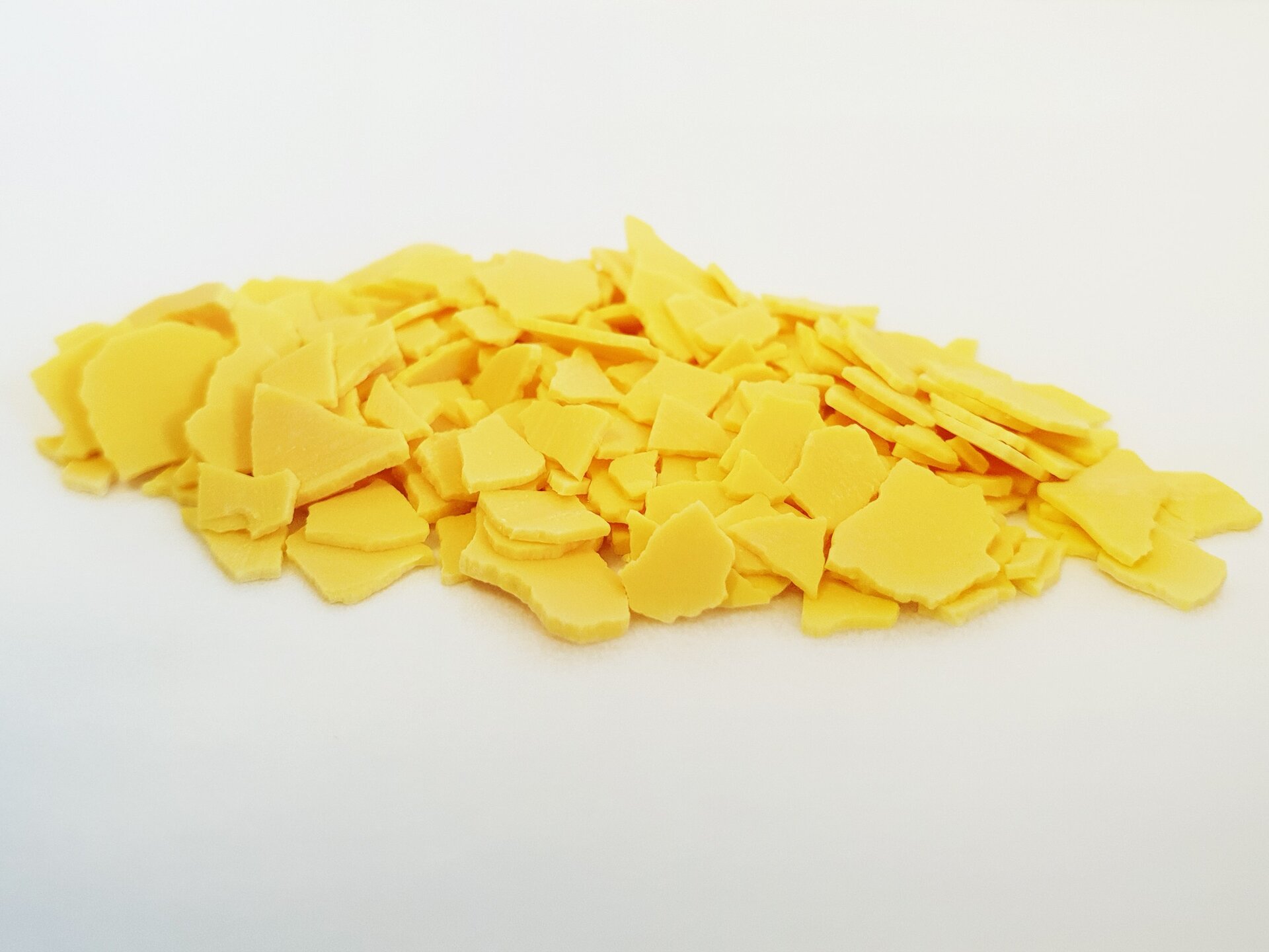 Na zdjęciu znajduje się pewna ilość siarczku sodu. To cienkie, płaskie kawałki żółtego ciała stałego.