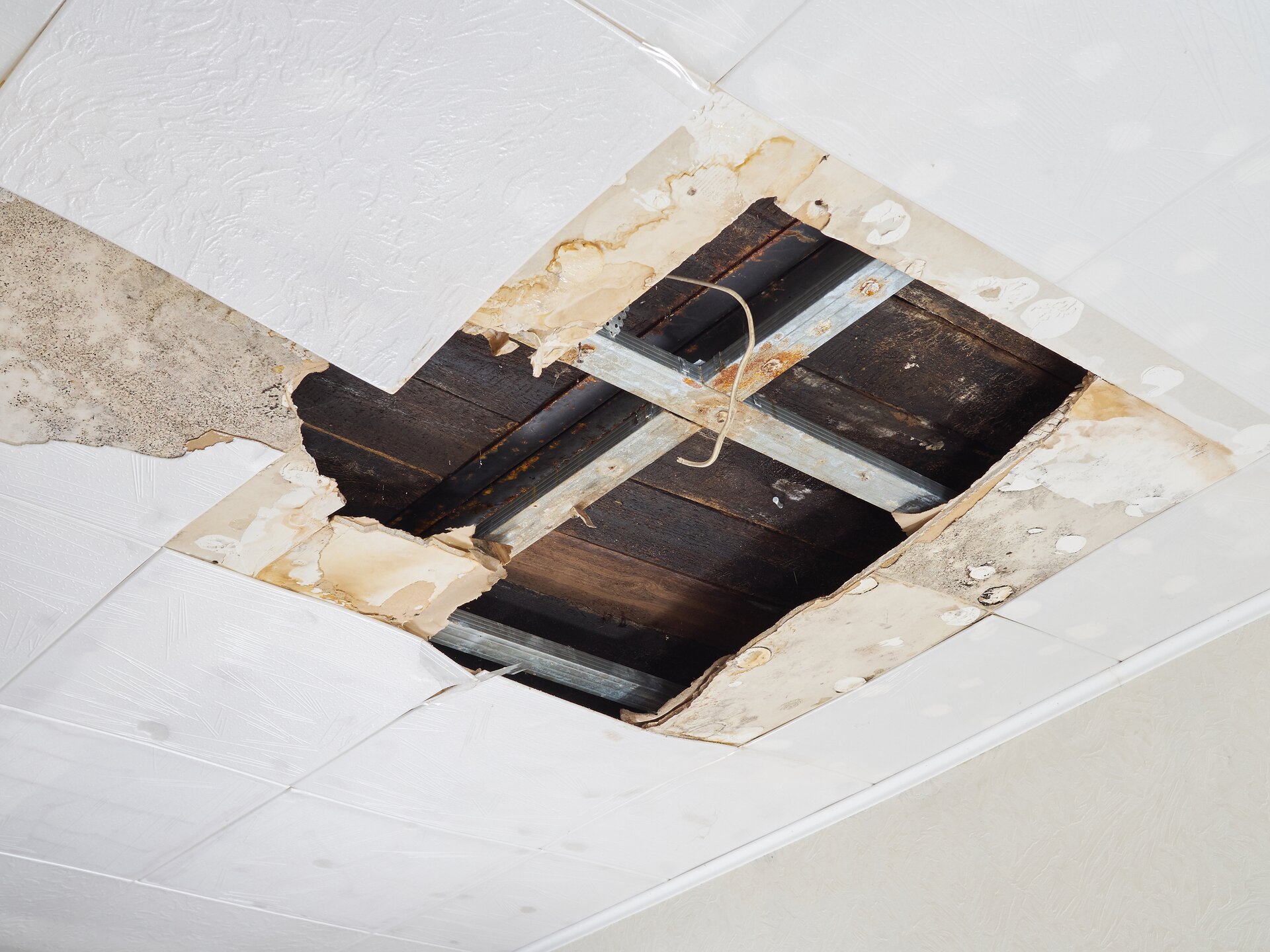 Zdjęcie przedstawia uszkodzenia izolacji dachów i poddasza. Widoczny jest fragment poddasza z pęknięciem. Pod spodem widać drewnianą konstrukcję.