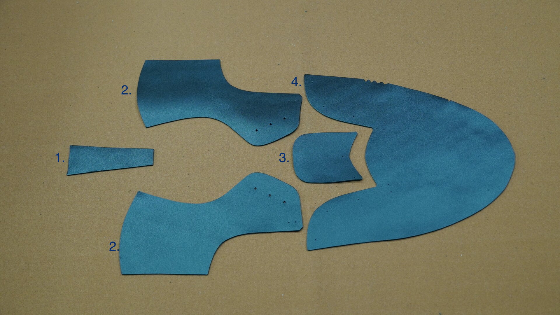 Zdjęcie przedstawia pięć kawałków skóry w różnych kształtach, które stanowią elementy cholewki. Nagranie tożsame z treścią.