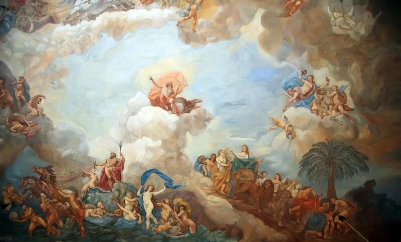 Zdjęcie przedstawia malowidło naścienne, na którym uwidoczniono mityczną scenę. Na chmurach, które łączą się z ziemią, zasiadają herosi i bogowie. W lewym, górnym rogu widać koła rydwanu zaprzęgniętego w białe rumaki pędzące po chmurach. W centrum na białym obłoku siedzi nagi mężczyzna z brodą, z wysuniętą prawą ręką w stronę nieba, po którym jedzie rydwan. Mężczyzna okryty jest jedynie suto drapowanym materiałem, który podwiewany jest przez wiatr. Po prawej stronie, na obłoku, zasiada naga kobieta jedząca winogrona w otoczeniu pulchnych amorków. Na ziemi, która łączy się z niebem poprzez kłęby mgły, znajduje się grupa osób zgromadzona wokół kobiety i dwóch lwów. Po lewej stronie, na wzburzonych falach morskich, znajduje się druga grupa, w której stoi Posejdon z trójzębem. Bóg prowadzi po wodzie rydwan zaprzęgnięty w dwa rumaki. Obok niego nagie kobiety, kąpiące się w wodzie.