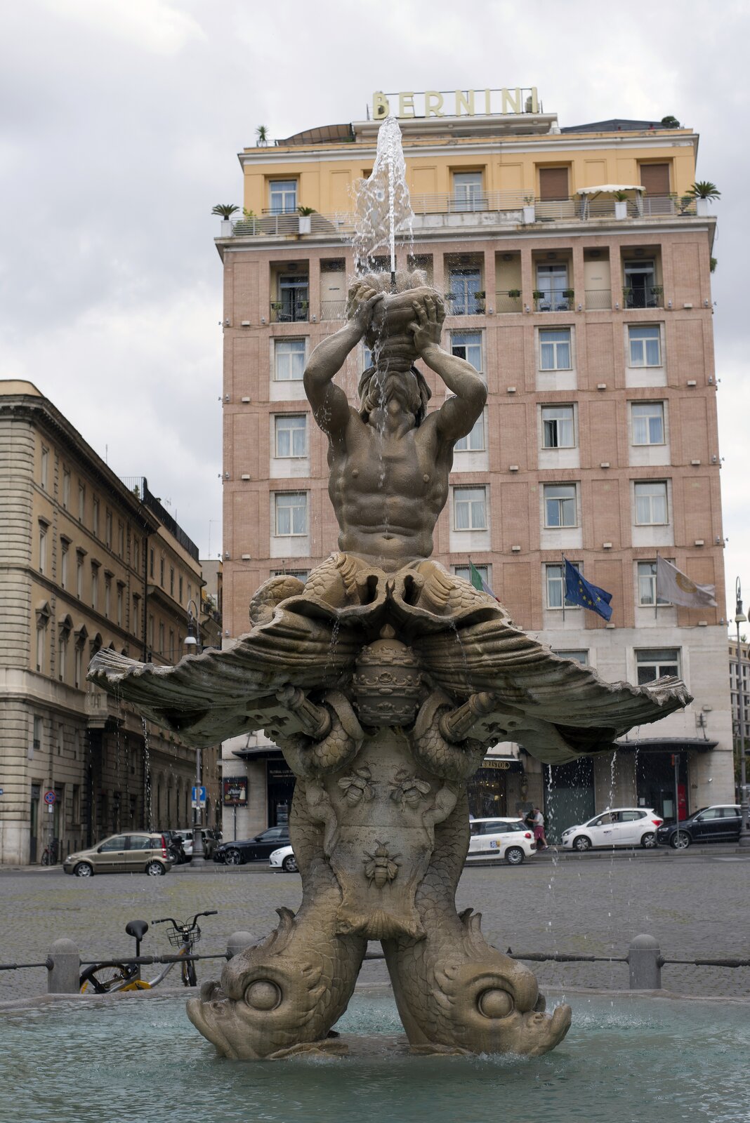 Ilustracja przedstawia fontannę Trytona (Fontana del Tritone) Gianlorenza Berniniego. W dolnej jej części znajdują się delfiny, na których ogonach została zamieszczona muszla z klęczącym, umięśnionym Trytonem. Mężczyzna, odchylając do tyłu głowę, gra na muszli, z której tryska strumień wody. Pomiędzy ogonami delfinów zostały wkomponowane papieskie insygnia oraz trzy pszczoły – element herbu rodu Barberinich. Fontanna została sfotografowana na tle architektury rzymskiej. 