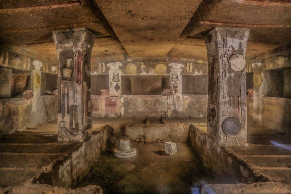 Na ilustracji przedstawiono ciemne wnętrze - jest to grobowiec, którego ściany i filary są ozdobione rzeźbionymi i malowanymi reliefami. Przedstawiają one przedmioty codziennego użytku, m.in.: naczynia, broń, narzędzia. 