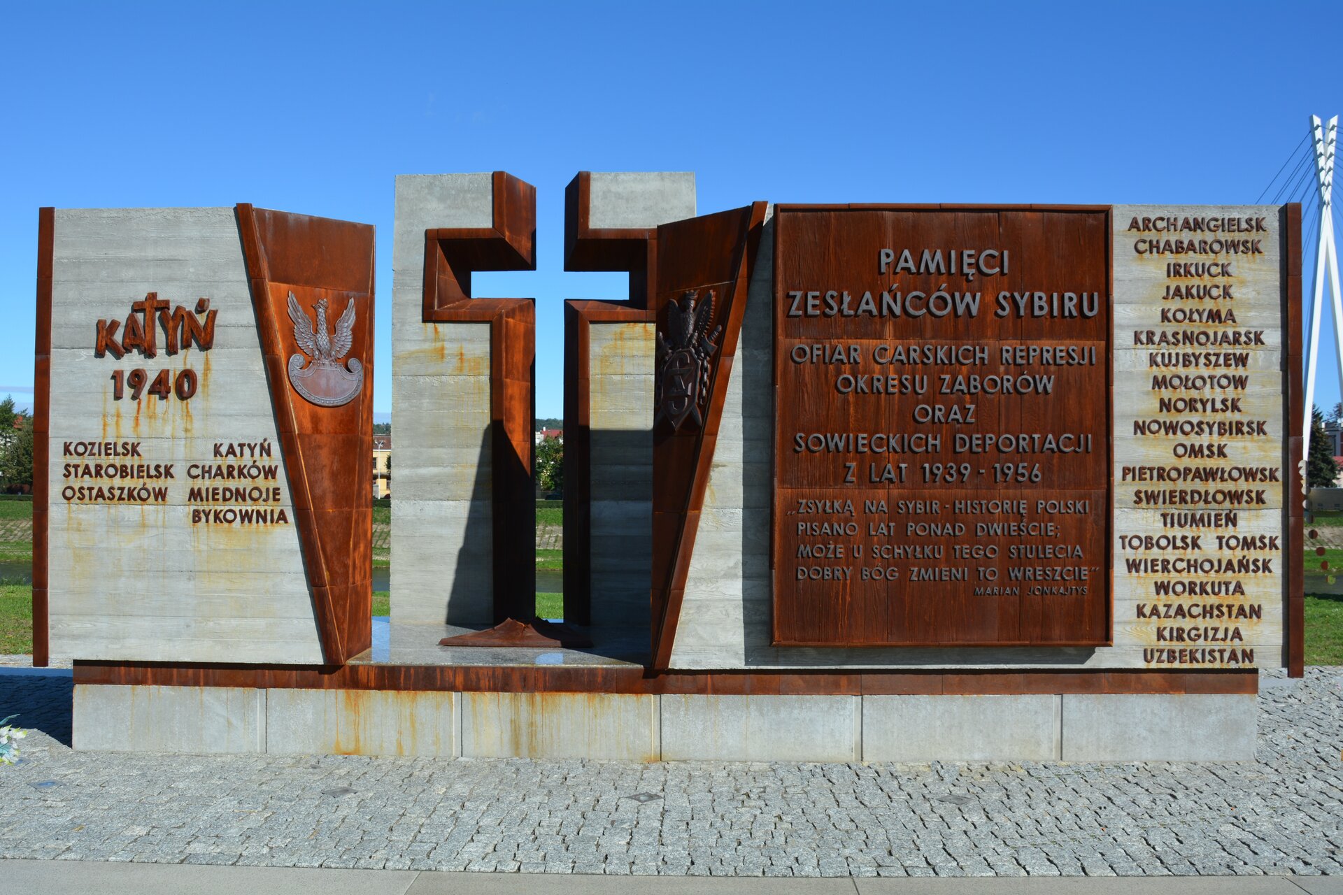 Zdjęcie przedstawia Pomnik Zesłańcom Sybiru i Ofiarom Katynia w Przemyślu. Na niewielkiej podmurówce wzniesione są duże, pionowe płyty, a niemal pośrodku nich wycięty w nich krzyż. Po lewej stronie widnieje napis Katyń 1940, Kozielsk, Starobielsk, Ostaszków, Charków, Miednoje, Bykownia. Po prawej stronie widać napis: Pamięci zesłańców Sybiru. Ofiar carskich represji okresu zaborów oraz sowieckich deportacji z lat 1939-1956. „Zsyłką na Sybir historię Polski pisano lad ponad dwieście, może u schyłku tego stulecia dobry Bóg zmieni to wreszcie”. Archangielsk, Chabrowsk, Irkuck, Jakuck, Kołyma, Krasnojarsk, Kujbyszew, Mołotow, Norylsk, Nowosybirsk, Omsk, Pietropawłowsk, Swierdłowsk, Tiumień, Tobolsk, Tomsk, Wierchojańsk, Workuta, Kazachstan, Kirgizja, Uzbekistan.