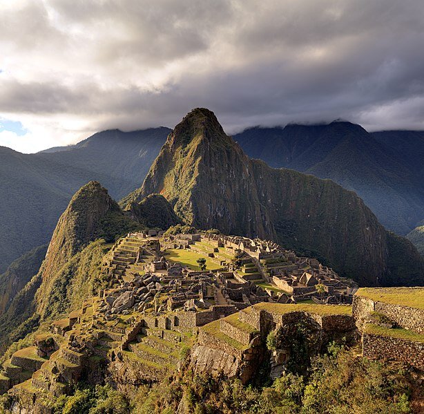 Zdjęcie przedstawia ruiny na przełęczy Huayna Picchu a Machu Picchu w Andach. Miasto składa się z dwóch części. W górnej, zwanej hanman, znajduje się: świątynia słońca, grobowiec królewski, pozostałości pałacu królewskiego oraz Intihuatana, czyli rytualny kamień, czyli największa inkaska świętość. W dolnej części znajdują się pozostałości domów mieszkalnych oraz warsztatów produkcyjnych. Na stromych zboczach otaczających miasto widać pozostałości tarasów uprawnych, z pionowymi ścianami z kamieni między nimi.
