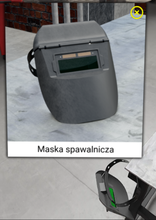 Ilustracji przedstawia okienko wyjaśniające nazwy przedmiotów, w którym widoczna jest maska spawalnicza. Na dole znajduję się pasek z podpisem przedmiotu, a w prawym głównym rogu krzyżyk zmykający całe okienko. 