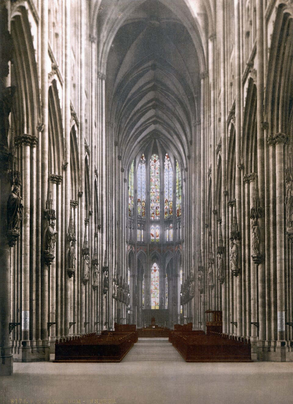 Wnętrze katedry św. Piotra i Najświętszej Marii Panny w Kolonii, widok na nawę główną i witraże w dwóch poziomach okien.
