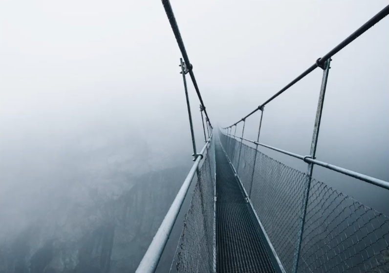 Scena przedstawia zdjęcia wiszącego mostu rozciągającego się nad koronami drzew. Pojawia się napis: Die längste Hängebrücke der Welt ist eine Attraktion für Kinder und Erwachsene.