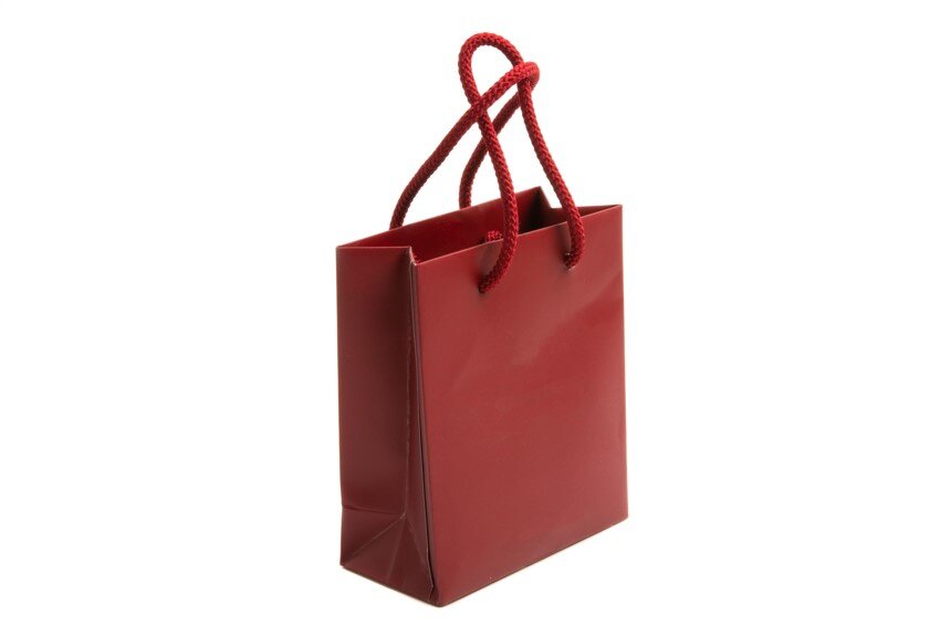 Zdjęcie przedstawia zadrukowaną, czerwoną torbę papierową z rączkami z czerwonego sznurka.

