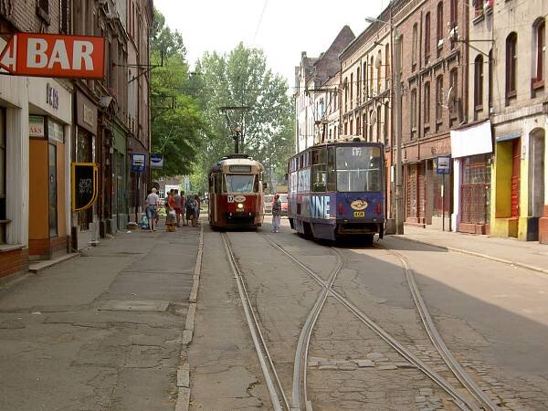 Zdjęcie przestawia ulicę w miasteczku. Po obu stronach stoją niskie kamienice, po ulicy jadą dwa tramwaje. W tle widnieją rozłożyste drzewa.