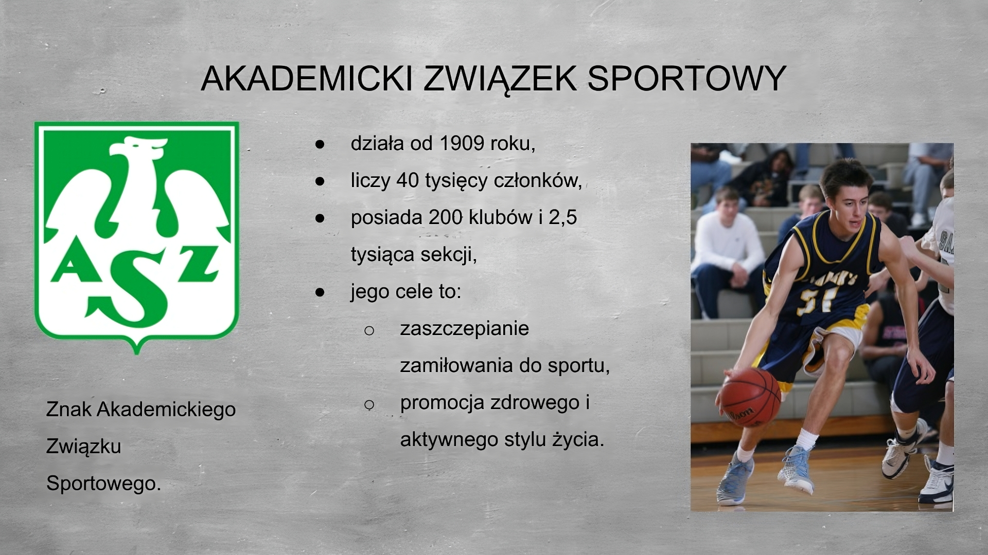 Slajd przedstawia szare tło, na górze tytuł: AKADEMICKI ZWIĄZEK SPORTOWY. Po lewej stronie grafika przedstawiająca znak Akademickiego Związku Sportowego - zielona tarcza z białym orłem i literami A Z S na dole. Po środku planszy wypunktowania: - działa od 1909 roku, - liczy 40 tysięcy członków, posiada 200 klubów i 2,5 tysiąca sekcji, - jego cele to: - zaszczepienie zamiłowania do sportu, - promocja zdrowego i aktywnego stylu życia. Po prawej stronie planszy zdjęcie przedstawiające kozłującego pomarańczową piłkę młodego koszykarza o brązowych włosach ubrany we fioletowo żółto biały strój i niebieskie buty. W tle widać siedzących na widowni kibiców.