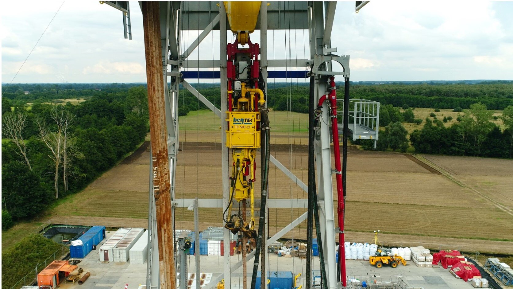 Na zdjęciu widać część wieży wiertniczej wiertni wyposażonej w głowice Top Drive. Głowice Top Drive, jest to połączenie silnika wrzeciona z głowicą płuczkową i zawiesiami elewatorowymi odpowiedzialne za przekazywanie momentu obrotowego na przewód wiertniczy. Na zdjęciu widoczne elementy to: Gęsia szyja, i stojak płuczkowy znajdujący się po prawej stronie wieży wiertniczej oraz silnik Top drive'u, gęsia szyja wrzeciona, głowica płuczkowa Top Drive'u i zawiesia elewatorowe znajdujące się po środku wieży wiertniczej.